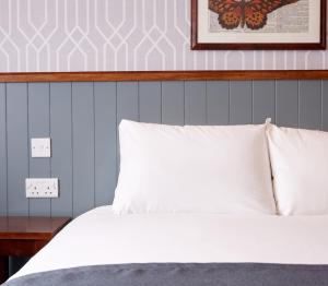 a bedroom with a white bed with a blue wall at Chase Inn By Greene King Inns in Nuneaton