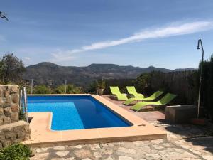 a swimming pool with green chairs next to a house at Casa rural Alojamiento Garganton in Cabrita