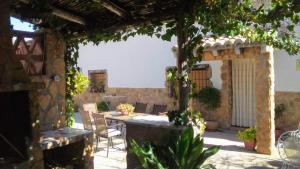 un patio avec une table et des chaises et un mur en pierre dans l'établissement Casa rural Alojamiento Garganton, à Cabrita