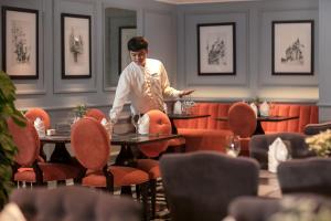 a man standing at a table in a restaurant at Anatole Hotel Hanoi in Hanoi