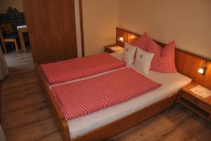 1 dormitorio con 1 cama con almohadas rojas y blancas en das Luggi Appartements, en Reith im Alpbachtal