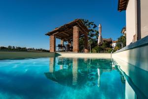 una piscina con pergolato e cielo blu di Cascina Allegria a Castelnuovo