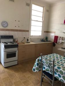 a kitchen with a stove and a table and a window at The Pink House in Walgett