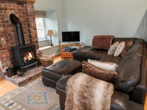 a living room with a leather couch and a fireplace at The Barn in Dalbeattie