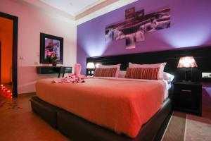 - une chambre avec un grand lit et un mur pourpre dans l'établissement Hôtel Suite Martil, à Martil