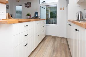 a kitchen with white cabinets and a wooden floor at Welcome in - Vakantiewoning met ruime tuin en open haard I Horizon 3 Renesse in Renesse