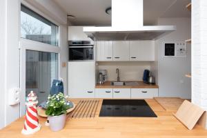 a kitchen with white cabinets and a wooden floor at Welcome in - Vakantiewoning met ruime tuin en open haard I Horizon 3 Renesse in Renesse +70 photos