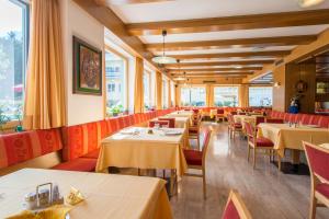 un restaurante con mesas, sillas y ventanas en Hotel Nocker, en Dobbiaco