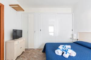 1 dormitorio con 1 cama con toallas y TV en Joy Home Apartments by BarbarHouse, en Maruggio