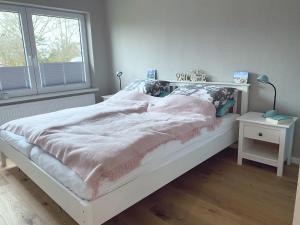 ein weißes Bett in einem Zimmer mit Fenster in der Unterkunft Sophienrast in Husum