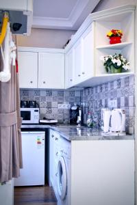 a kitchen with white cabinets and a washer and dryer at Abano view apartment in Tbilisi City
