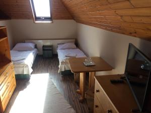 a room with two beds and a table and a tv at Vénusz Panzió és Vendéglő in Bagod