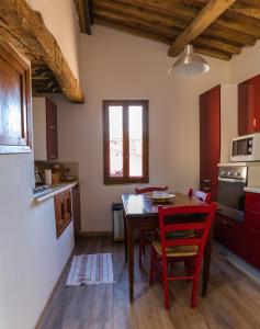 cocina con mesa de madera y sillas rojas en Appartamento Porta Pispini, en Siena