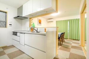 a kitchen with white cabinets and a green curtain at Zenith's House in Osaka