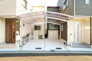 a house with a covered patio with a bike in it at Zenith's House in Osaka