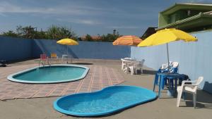 a swimming pool with a table and chairs and an umbrella at Hotel Rainha in Itapoa