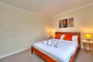 a bedroom with a bed with orange and white pillows at Hampson House Stevenage by PAY AS U STAY in Stevenage