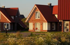 une rangée de maisons aux toits rouges dans l'établissement Der Deichhof - Ferienwohnungen, à Wremen