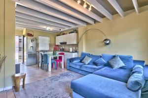 a living room with a blue couch and a kitchen at Milton mews in Cape Town