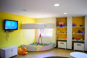 HotSprings ApartHotel في كالدس نوفاس: غرفة أطفال بها منطقة لعب بها لعبة