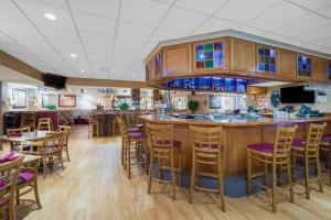 a restaurant with a bar and tables and chairs at Wyndham Garden Otsego-Minneapolis in Otsego