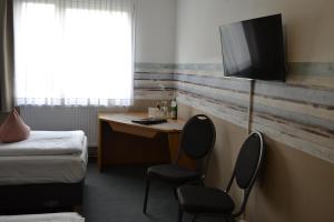 a room with a desk with two chairs and a television at Hotel-Café-Galerie in Garbsen