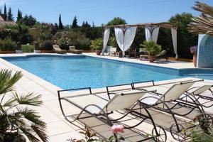 - une piscine avec des chaises et un kiosque dans l'établissement Gîtes maisons de vacances Domaine la Chamade Carpentras, à Carpentras