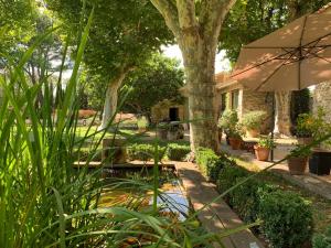 un jardín con mesa y sombrilla en La Melizanne, en Fuveau