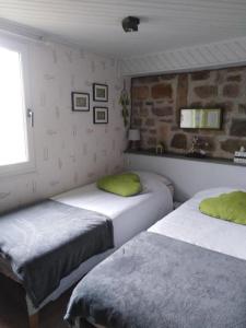 two beds in a room with a brick wall at Clair Matin in Villeneuve-dʼAllier