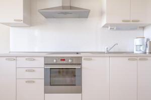 una cocina con armarios blancos y horno plateado en Luxury Apartments Villa Luce, en Malinska