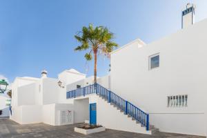 - un bâtiment blanc avec des escaliers bleus et un palmier dans l'établissement Conylanza Tabayba Blue, à Costa Teguise