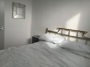 ヘムズビーにある245 Sundownerのベッドルーム1室(白いシーツと壁に時計付)