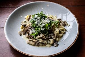 a white plate of pasta with mushrooms and cheese at The Royal Hotel in Kirkby Lonsdale