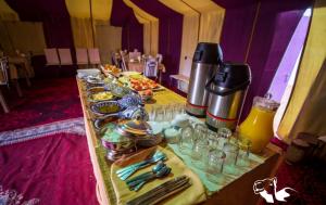 a table with plates of food and glasses on it at Sahara Desert Camp in Merzouga