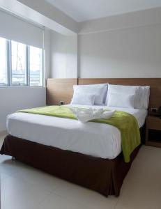 Un dormitorio con una cama grande con una manta verde. en Hotel Monte Cafeto INN, en Pichanaki