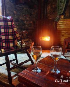 two glasses of wine sitting on a wooden table at Vila Mali Tornik in Zlatibor