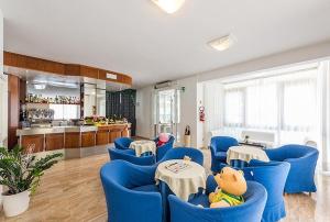 a room with blue chairs and tables and a kitchen at Hotel Palladio B&B in Cervia
