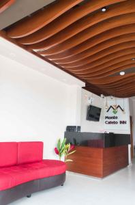 a living room with a red couch and a tv at Hotel Monte Cafeto INN in Pichanaki