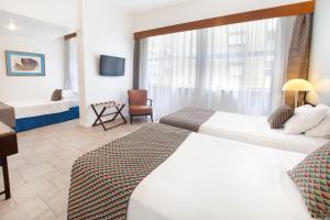 a hotel room with two beds and a television at Savoy Othon in Rio de Janeiro