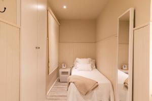 a small bedroom with a bed and a mirror at Chic Gran Via Apartment in Barcelona