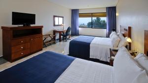 a hotel room with two beds and a flat screen tv at Holiday Inn Veracruz-Boca Del Rio, an IHG Hotel in Veracruz