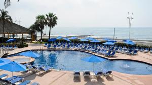 una piscina con sillas y sombrillas azules y el océano en Holiday Inn Veracruz-Boca Del Rio, an IHG Hotel, en Veracruz