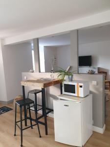 a kitchen with a table with a microwave and stools at La jolie chambre in Javrezac