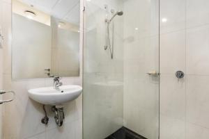 a white bathroom with a sink and a shower at Central Melbourne CBD Apartment with Gym and Pool in Melbourne