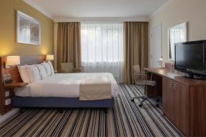 a hotel room with a bed and a desk and a television at Holiday Inn Stoke on Trent M6 Jct15 by IHG in Stoke on Trent