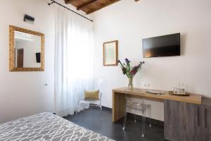 a bedroom with a desk and a television on the wall at Sette Angeli Rooms in Florence