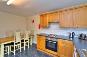 a kitchen with wooden cabinets and a table with chairs at Hampson House Stevenage by PAY AS U STAY in Stevenage