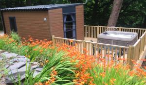 une petite maison avec un jardin fleuri devant elle dans l'établissement P72 - Swift Pod with Hot Tub, à Bangor
