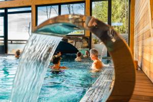 a group of people in a swimming pool with a water slide at Domaine du Hirtz, Restaurant & Spa in Wattwiller