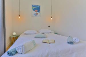 białe łóżko z ręcznikami i książką w obiekcie Maison Bianchi - Civette Garibaldi w Nicei